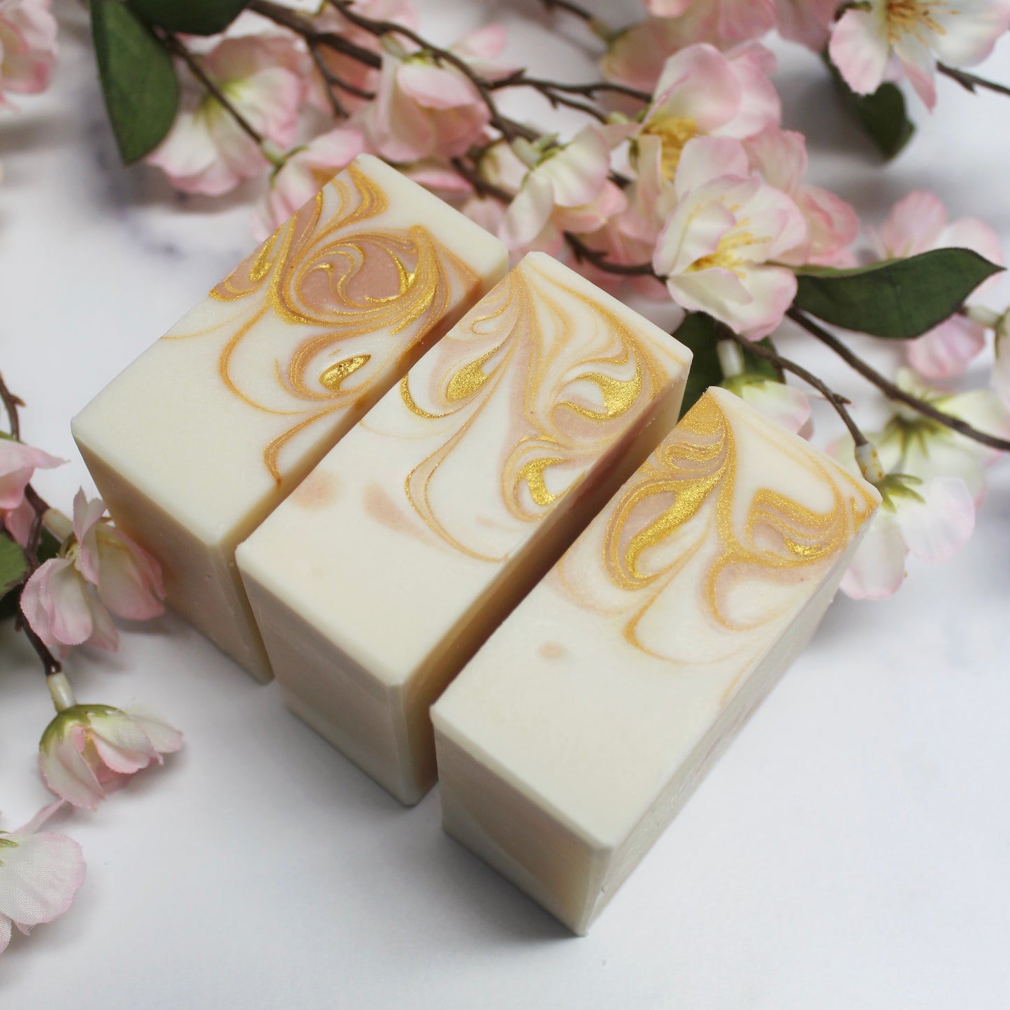 Cream colored soap bar with pink and gold swirls on top.